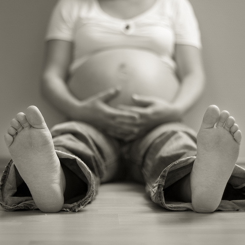 Бременна жена, седнала на пода