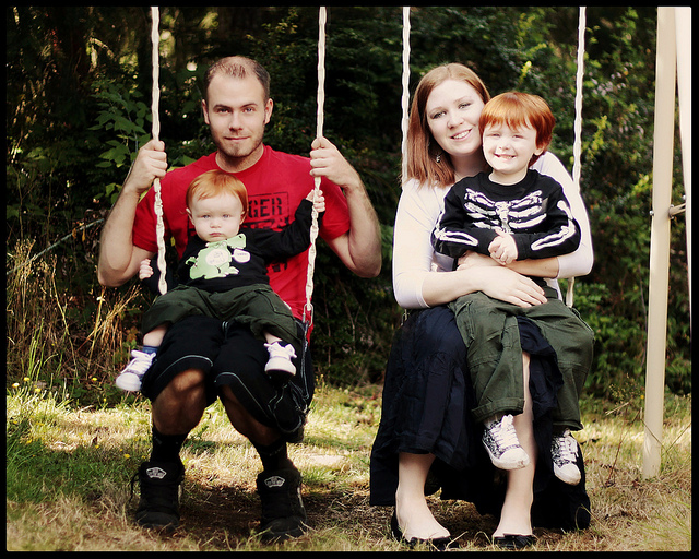 Семейство с две деца на люлки в парка